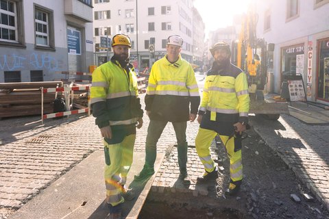 Drei Monteure in Warnkleidung auf einer Baustelle in der Zürcher Altstadt.