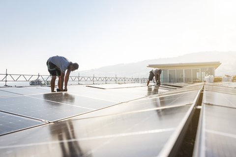 Zwei Männer installieren eine Solaranlage auf einem Dach