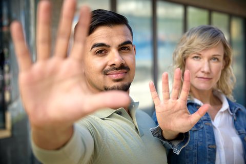 Zwei Mitarbeitende machen mit erhobenen Händen ein «Stopp»-Zeichen, um Abgrenzung zu signalisieren.