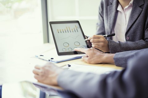 Bürosituation mit zwei Personen, die Grafiken auf einem Tablet besprechen