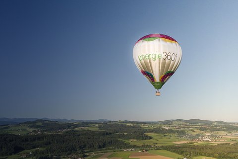 Ein Heissluftballon mit Energie 360° Logo schwebt über einer grünen Landschaft