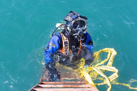 Ralf Zwahlen steigt in Tauchmontur über eine Eisenleiter in den See.