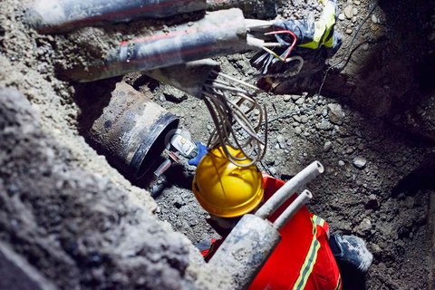 Un homme travaille sur une conduite dans une excavation