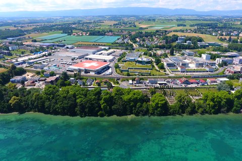 Luftbild mit Blick vom Genfersee über das Industriegebiet ins Umland von Tolochenaz.