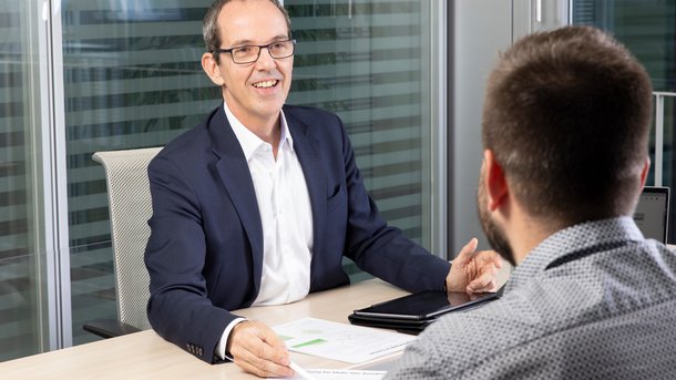 Zwei Männer im Gespräch mit Unterlagen auf einem Sitzungstisch