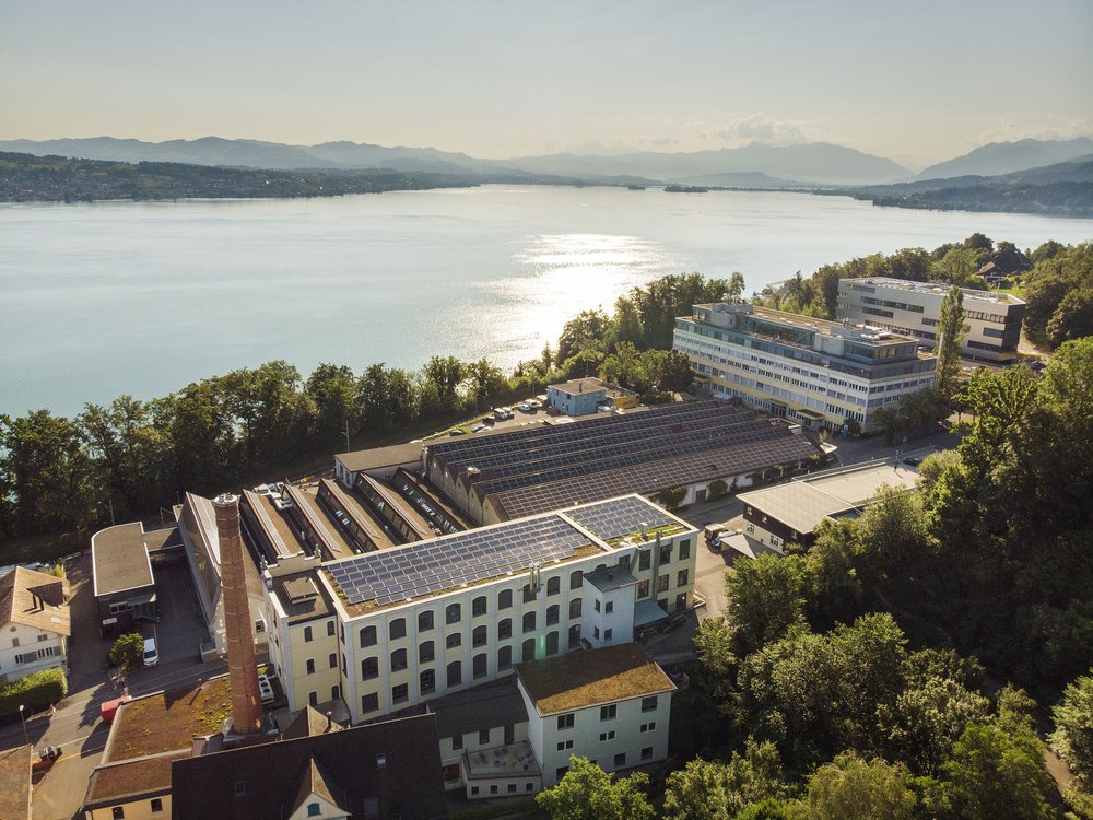 Le tuwagareal à Wädenswill. Des panneaux solaires sont visibles sur les toits, avec le lac de Zurich en arrière-plan.