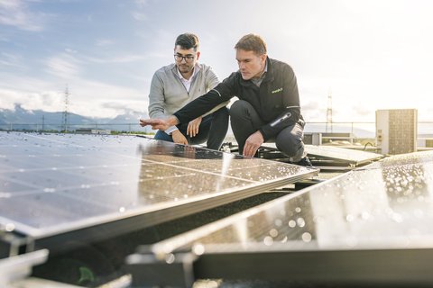 Zwei Männer begutachten eine Solaranlage aus der Nähe