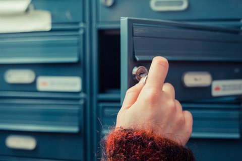Main ouvrant une boîte aux lettres