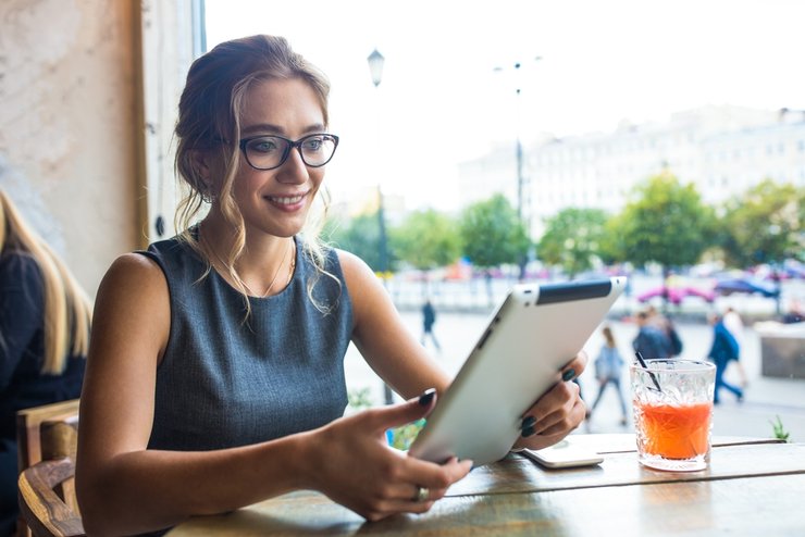 Eine Frau arbeitet an einem Tablet mit einem Getränk in einem Café